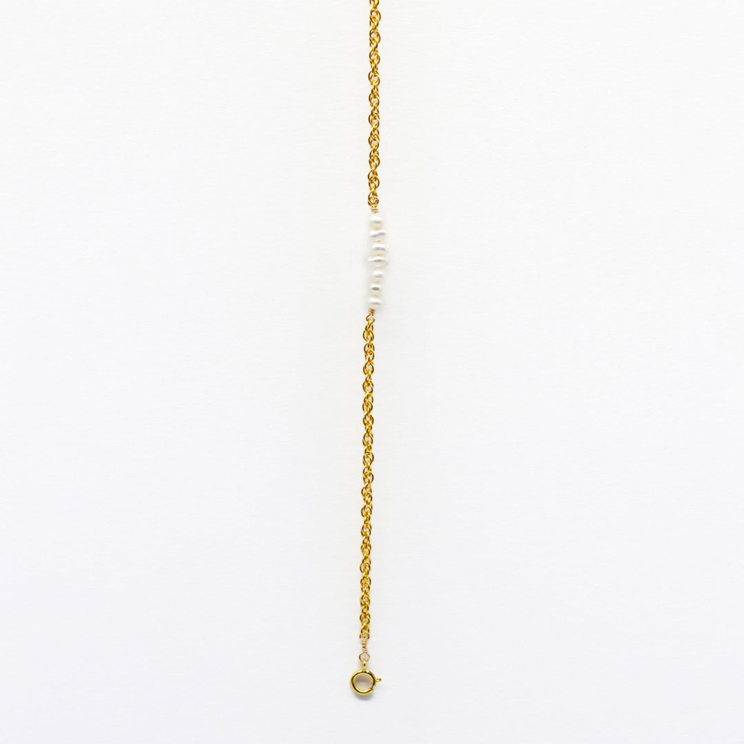 Gold necklace with small beads on a white background