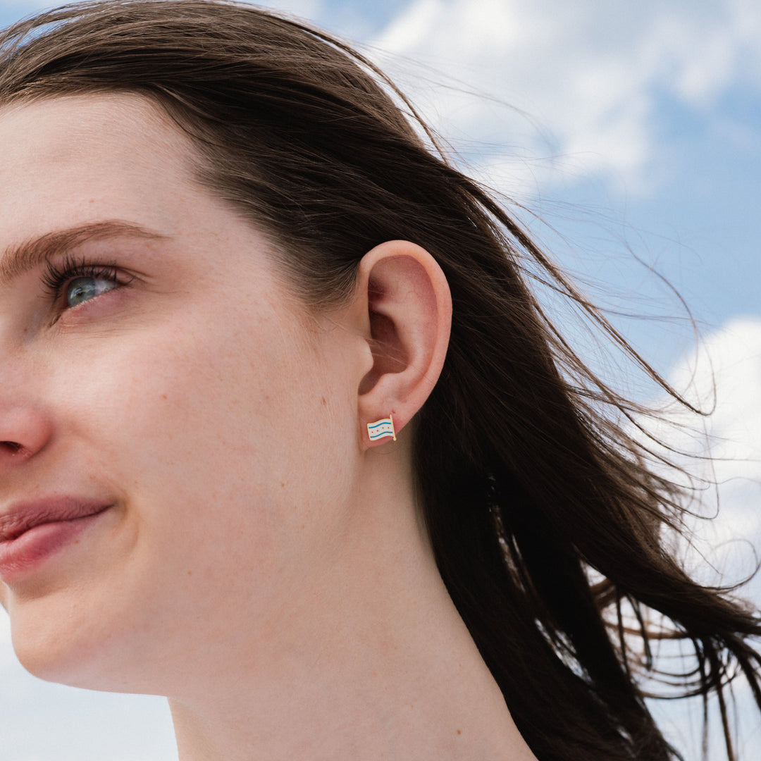 Close-up of a woman wearing a colorful earring with a blue sky background