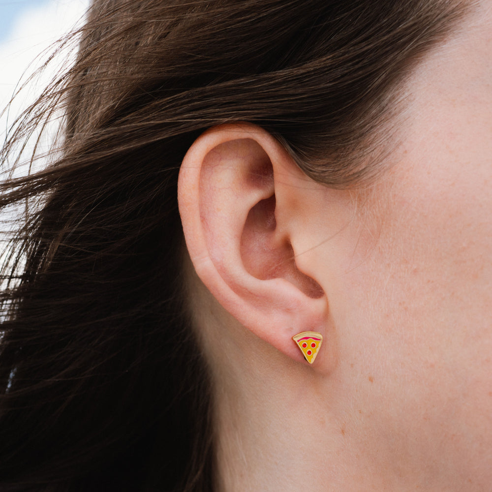 Close-up of an ear wearing a pizza slice earring with a blurred background
