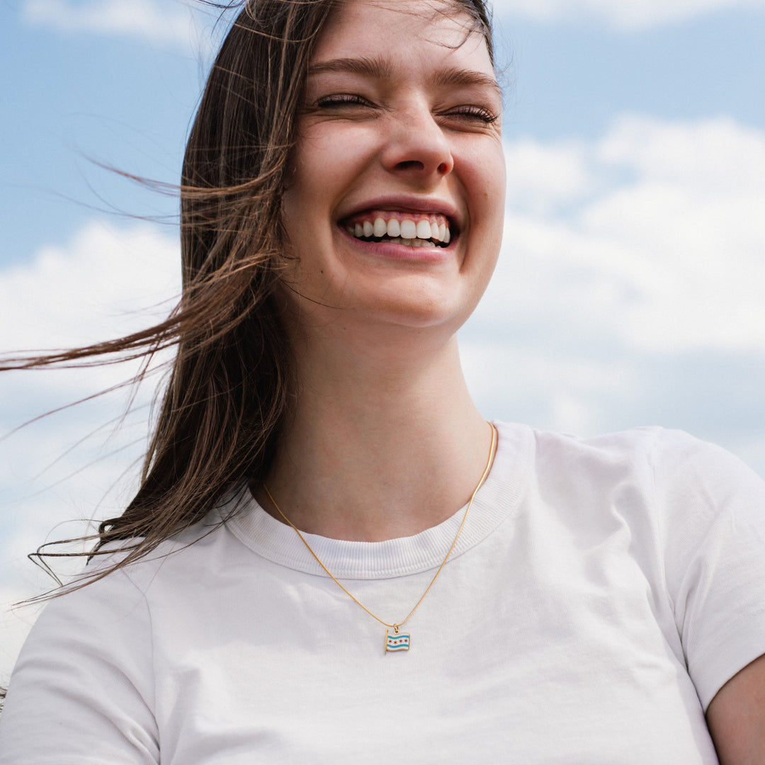 Woman wearing a necklace with a blue pendant against a blue sky.