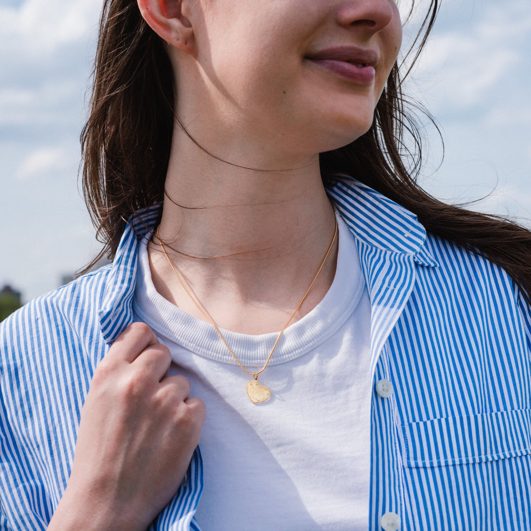 Person wearing a blue and white striped shirt with a necklace outdoors