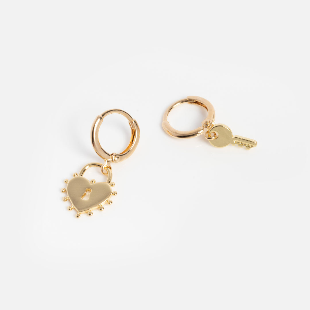 Gold hoop earrings with heart-shaped lock and key charms on a white background