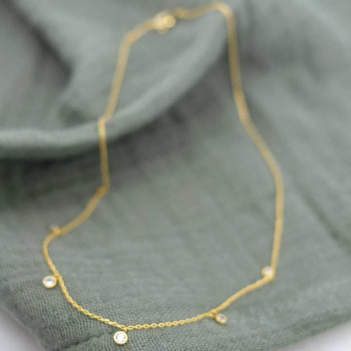 Gold necklace on a green fabric background