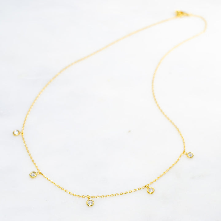 Gold necklace with small heart charms on a white background