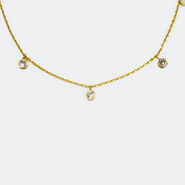 Gold necklace with small round pendants on a white background