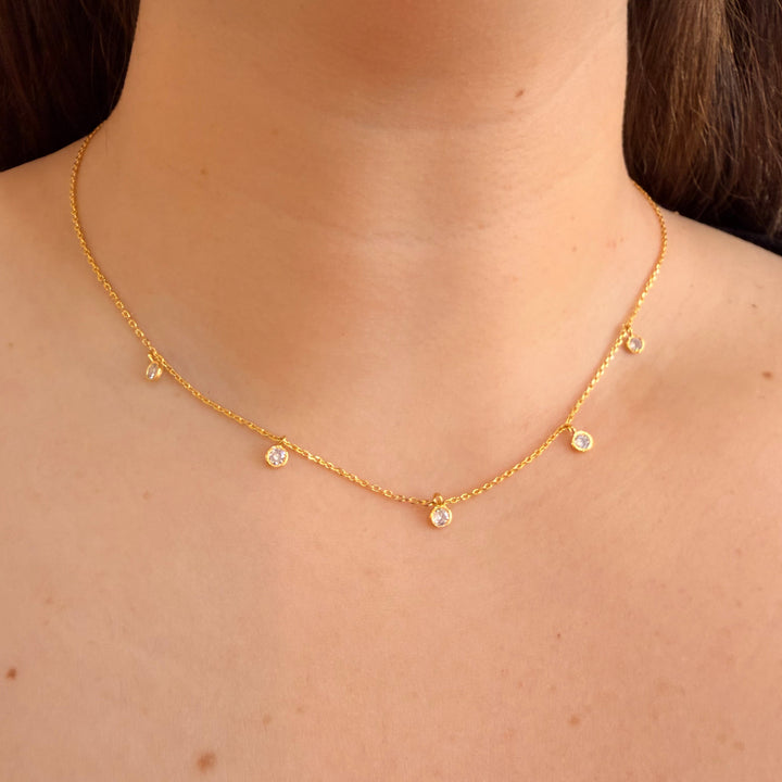 Gold necklace with small beads on a person's neck