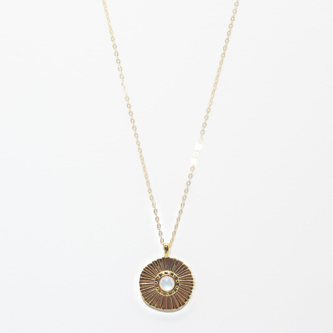 Gold necklace with a round pendant on a white background