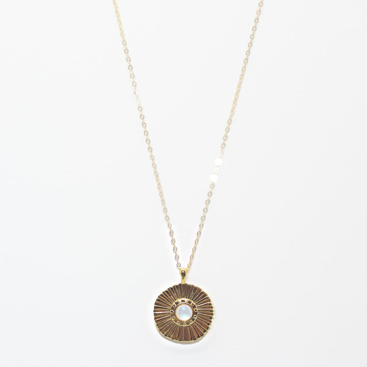 Gold necklace with a round pendant on a white background