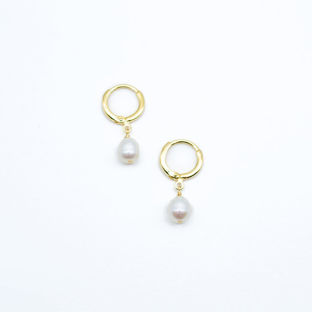 Gold hoop earrings with pearl drops on a white background