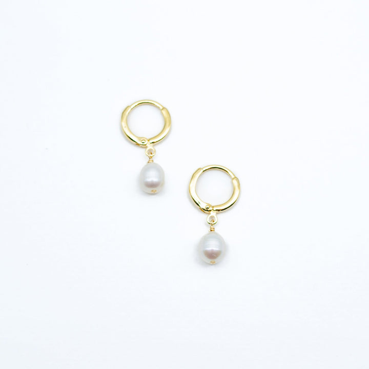 Gold hoop earrings with pearl drops on a white background