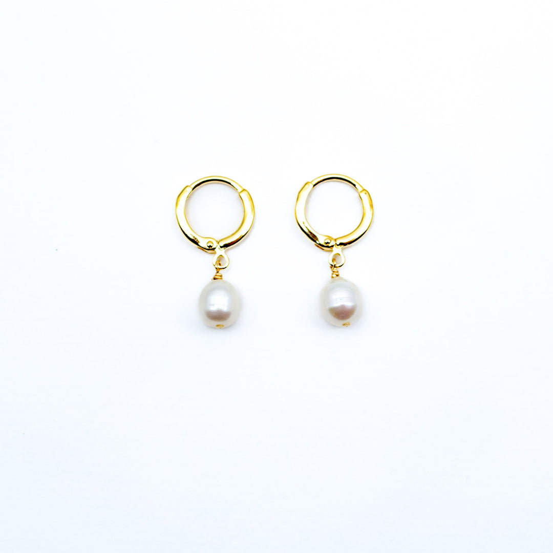 Pair of gold hoop earrings with pearl drops on a white background