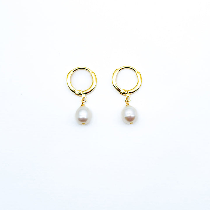 Pair of gold hoop earrings with pearl drops on a white background