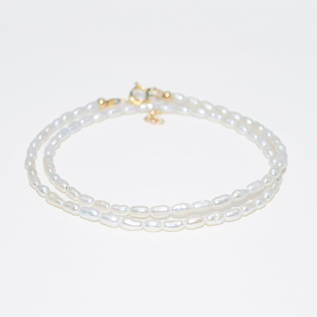 Pearl necklace with gold clasp on a light gray background