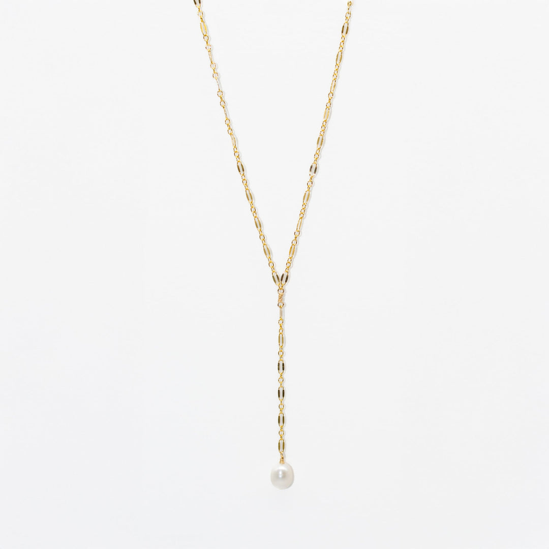 Gold necklace with a single pearl pendant on a light gray background