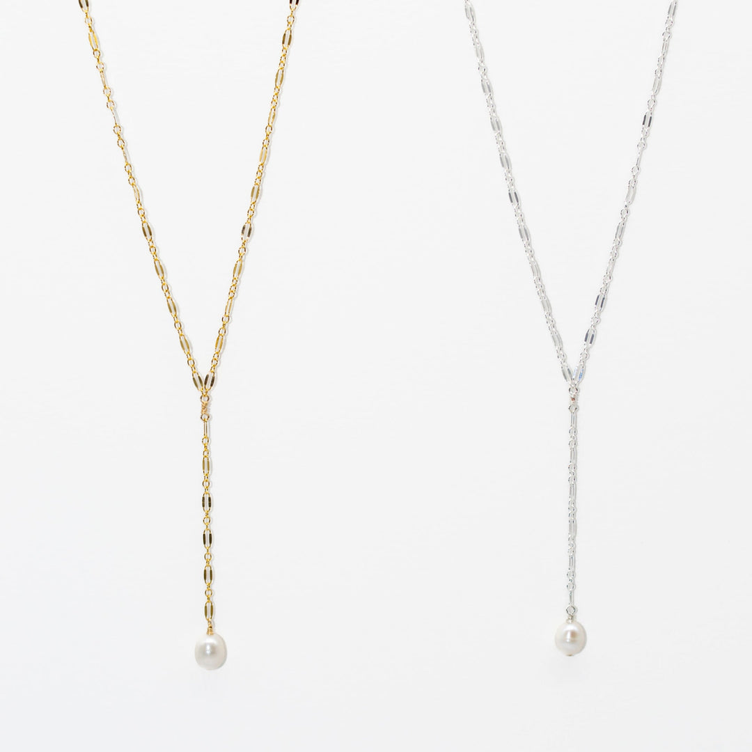 Two pearl necklaces, one gold and one silver, on a white background.