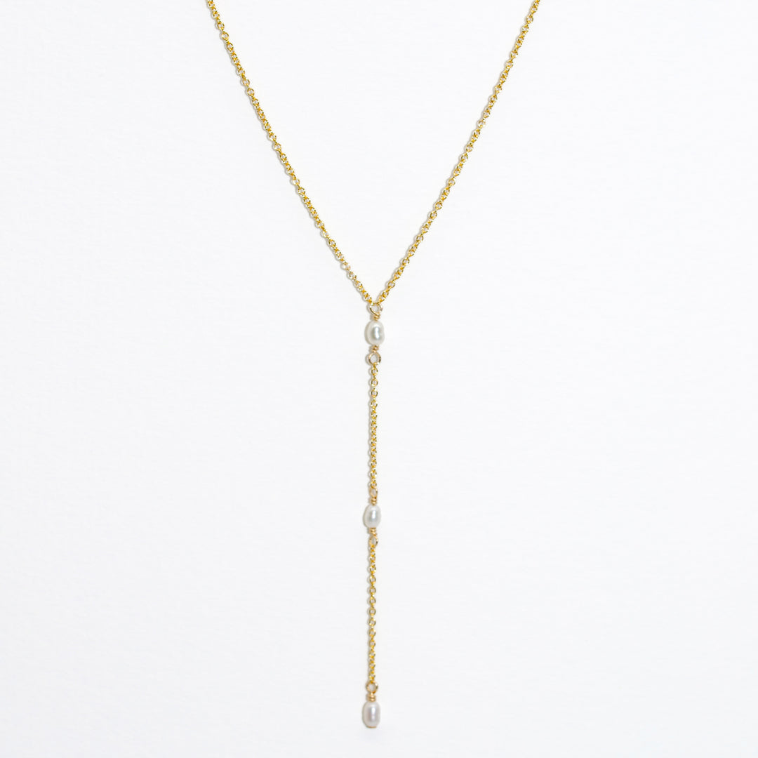 Gold necklace with pearl drops on a white background