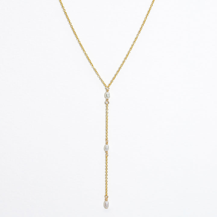 Gold necklace with pearl drops on a white background