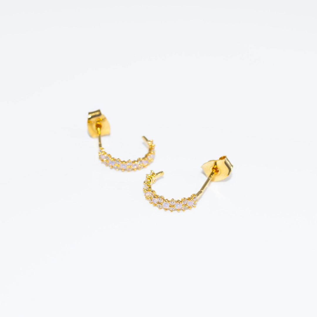Gold hoop earrings with small stones on a white background