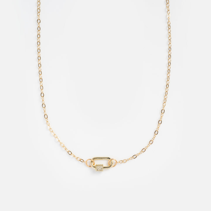 Gold necklace with a lock-shaped pendant on a light beige background