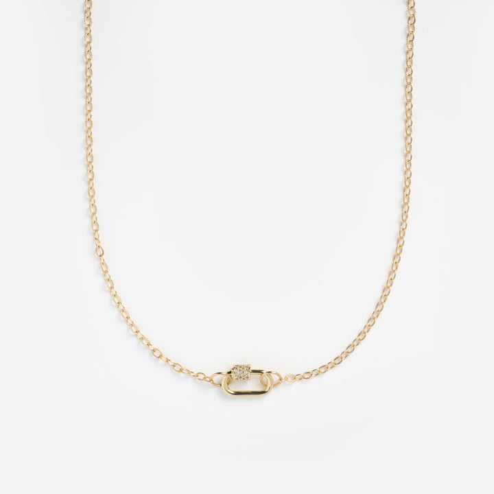 Gold necklace with a small pendant on a light gray background
