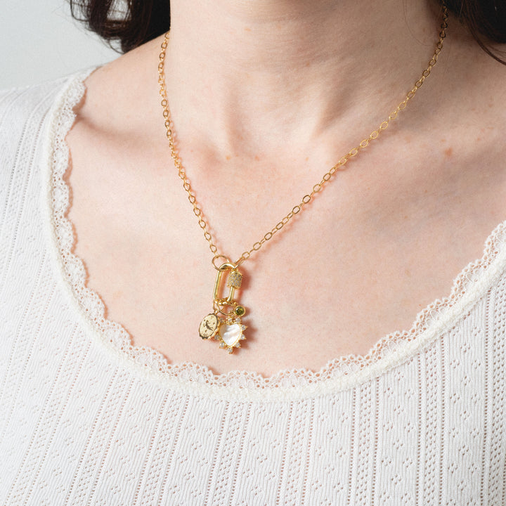 Gold necklace with a pendant on a person wearing a white sweater.