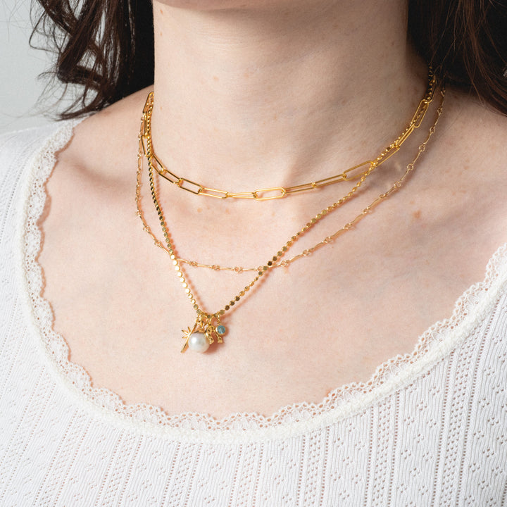 Gold necklaces on a person wearing a white top