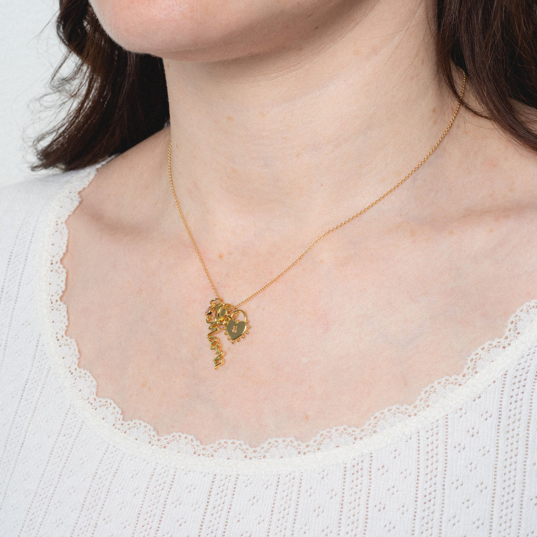 Gold necklace with a green pendant worn by a person in a white sweater.