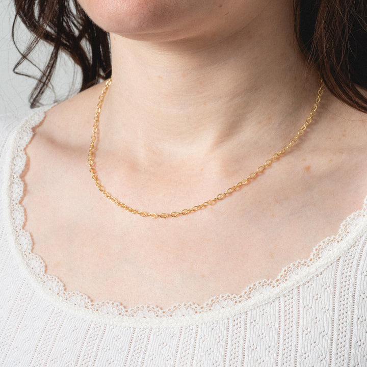 Gold necklace worn by a person with a white top