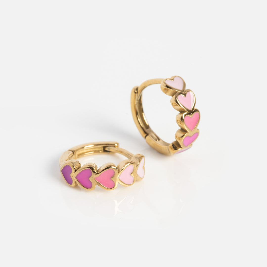 Gold hoop earrings with pink heart designs on a white background
